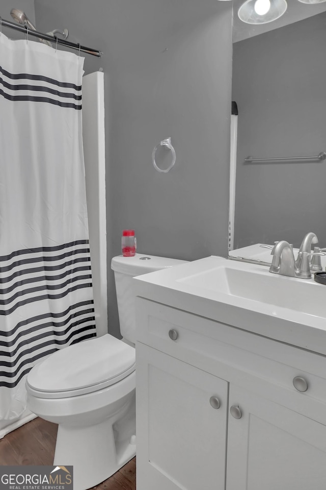 full bath featuring vanity, wood finished floors, toilet, and curtained shower