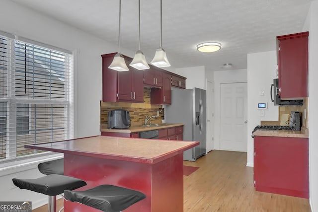 kitchen featuring stainless steel fridge, a sink, tasteful backsplash, light wood finished floors, and dishwasher