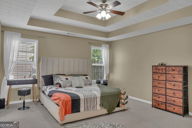bedroom featuring baseboards, carpet floors, a tray ceiling, and a ceiling fan