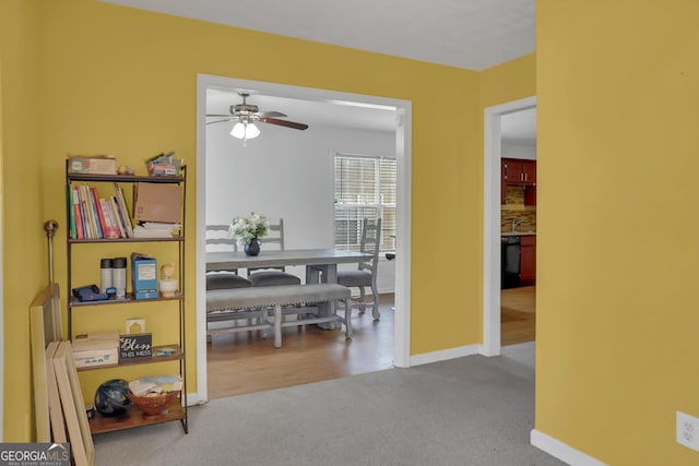 carpeted dining room with ceiling fan, baseboards, and a sink