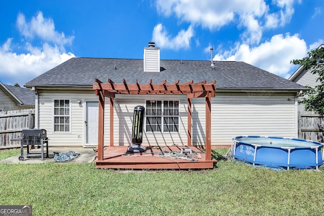 rear view of property featuring a pergola, a wooden deck, a chimney, and roof with shingles