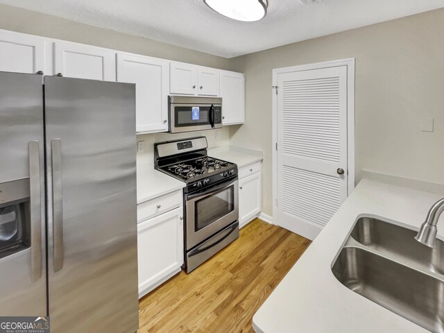 2190 River Heights Ct SE, Marietta, GA 30067 - kitchen featuring stainless steel appliances, light countertops, white cabinetry, and light wood-style flooring