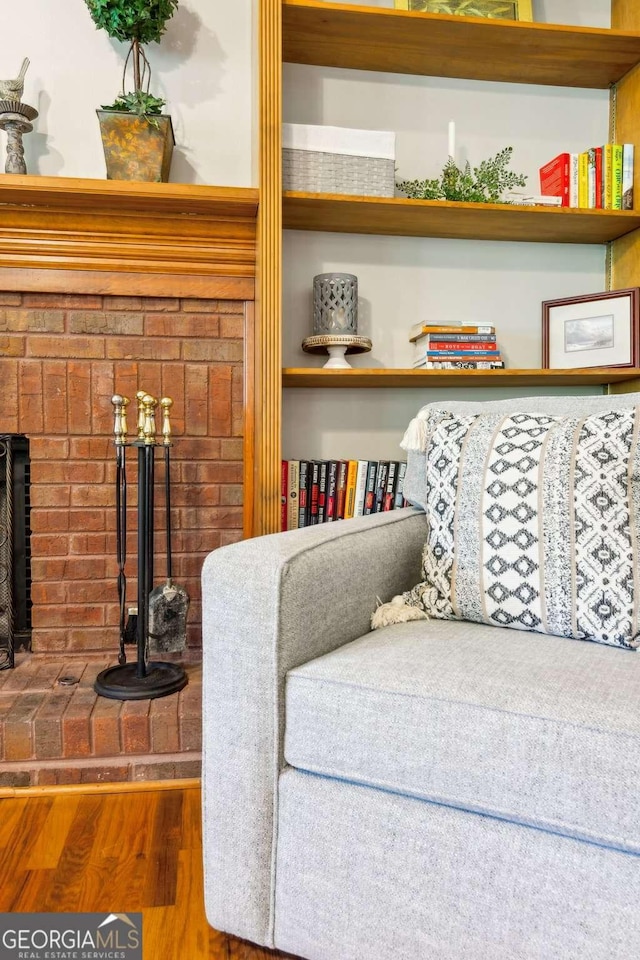 sitting room with wood finished floors and a brick fireplace