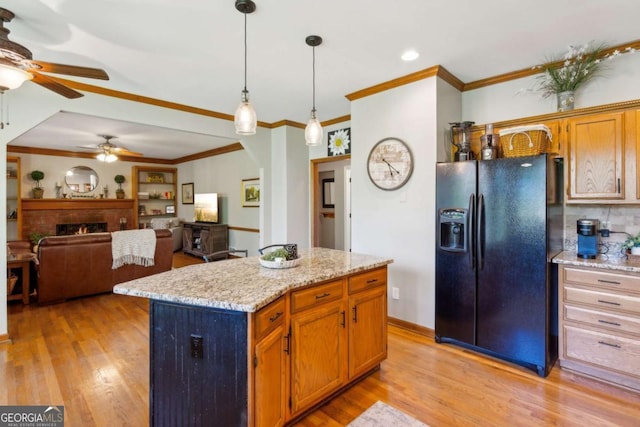 kitchen with black fridge with ice dispenser, ceiling fan, light wood-type flooring, decorative light fixtures, and a center island
