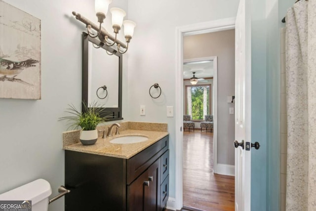 full bathroom featuring vanity, toilet, wood finished floors, a ceiling fan, and baseboards