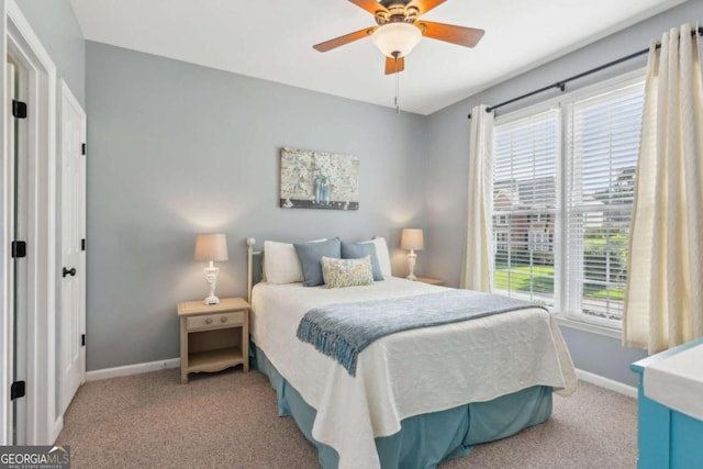 carpeted bedroom featuring baseboards, multiple windows, and ceiling fan
