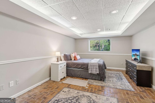 bedroom with baseboards, a raised ceiling, and recessed lighting
