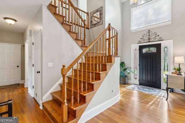 entrance foyer with wood finished floors, a high ceiling, stairs, and baseboards