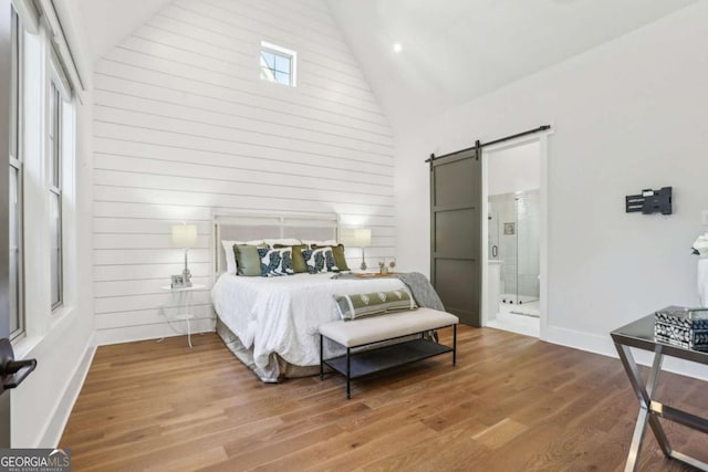 190 Arbor Garden Cir, Newnan, GA 30265 - bedroom featuring a barn door, high vaulted ceiling, wood finished floors, baseboards, and connected bathroom