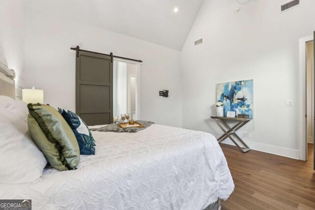 190 Arbor Garden Cir, Newnan, GA 30265 - bedroom with a barn door, wood finished floors, baseboards, high vaulted ceiling, and recessed lighting