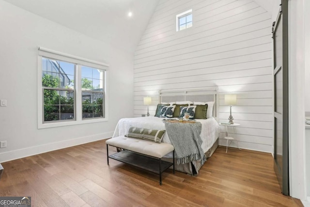 190 Arbor Garden Cir, Newnan, GA 30265 - bedroom with high vaulted ceiling, hardwood / wood-style flooring, a barn door, baseboards, and recessed lighting