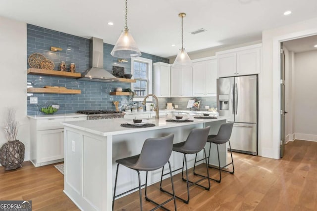 190 Arbor Garden Cir, Newnan, GA 30265 - kitchen with stainless steel fridge, wall chimney range hood, backsplash, white cabinets, and light wood-type flooring