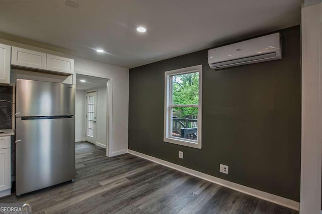1772 Martin Pl SE, Smyrna, GA 30080 - kitchen featuring freestanding refrigerator, an AC wall unit, white cabinetry, dark wood-type flooring, and baseboards