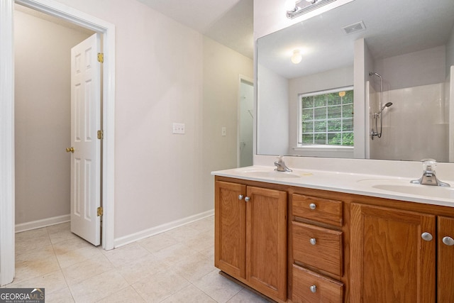 full bath with a shower, double vanity, baseboards, and tile patterned floors