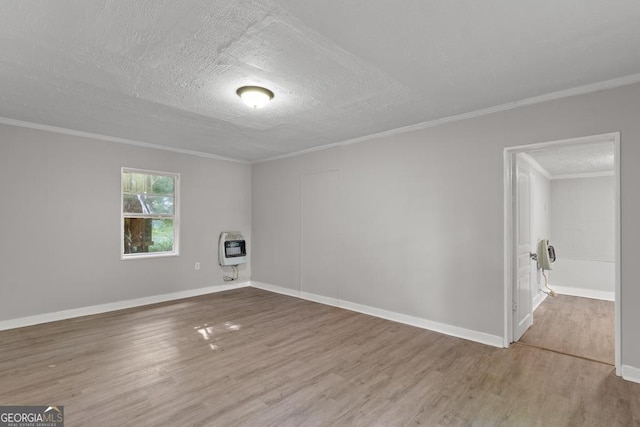 unfurnished room with heating unit, wood finished floors, ornamental molding, a textured ceiling, and baseboards