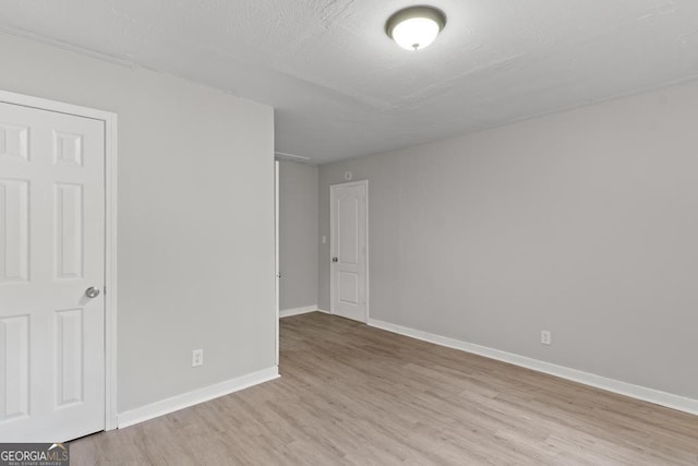 empty room featuring light wood-type flooring and baseboards