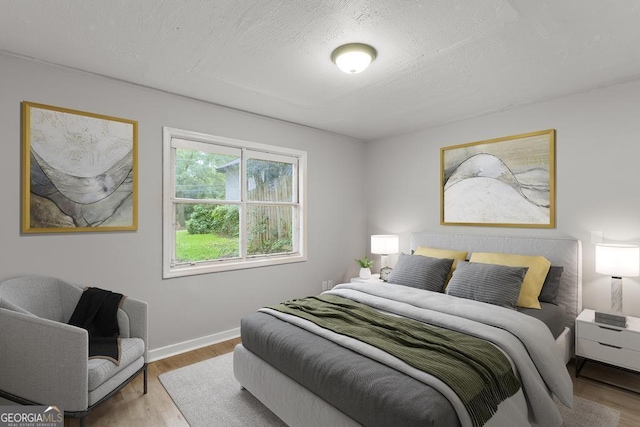 bedroom featuring wood finished floors, baseboards, and a textured ceiling
