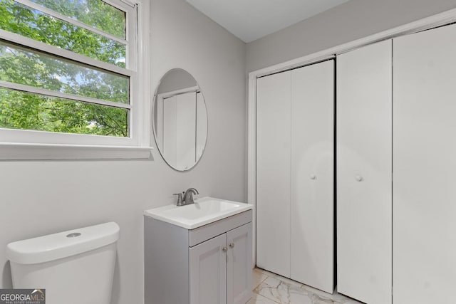 bathroom with marble look tiles, toilet, and vanity