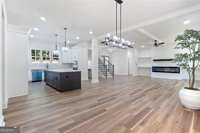 5567 Tyree Rd, Winston, GA 30187 - kitchen with appliances with stainless steel finishes, light countertops, light wood-style flooring, a glass covered fireplace, and tasteful backsplash