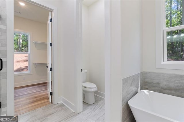 5567 Tyree Rd, Winston, GA 30187 - bathroom with toilet, a soaking tub, baseboards, and wood finished floors