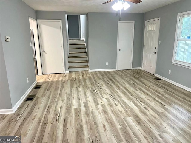 3045 Revere Cir, Snellville, GA 30039 - unfurnished living room featuring a ceiling fan, light wood-style floors, baseboards, and stairs