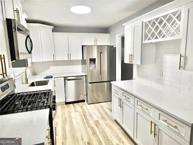 3045 Revere Cir, Snellville, GA 30039 - kitchen featuring stainless steel appliances, a sink, decorative backsplash, white cabinetry, and light wood finished floors