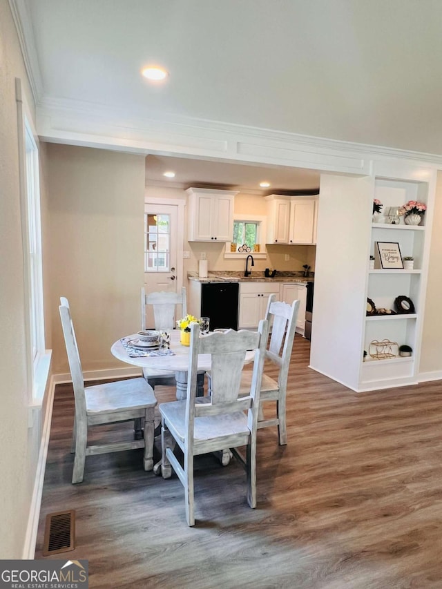 dining room featuring crown molding, wood finished floors, recessed lighting, built in features, and baseboards