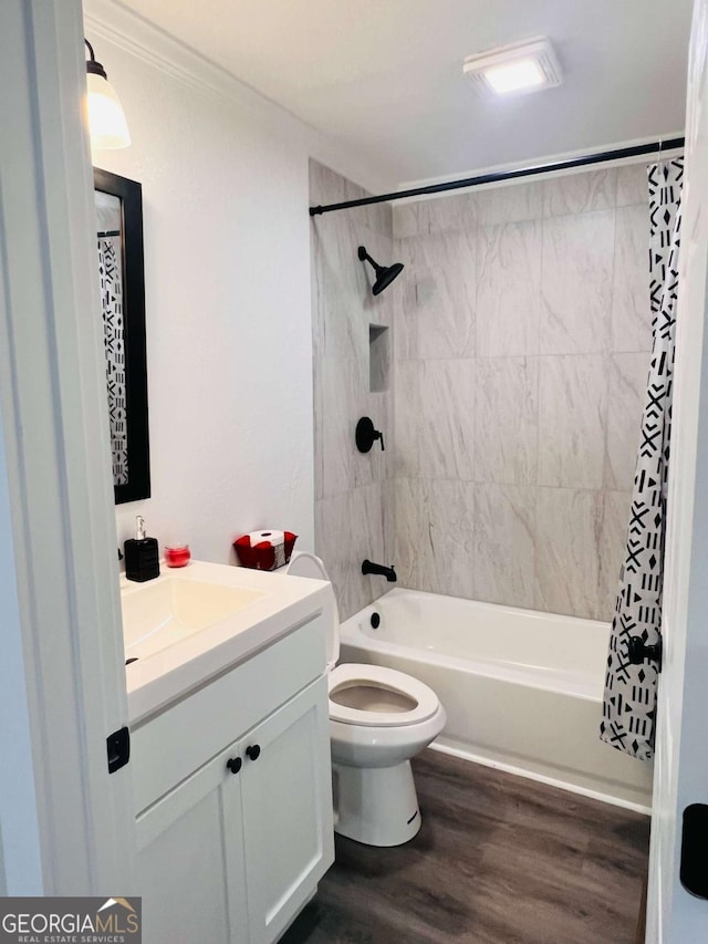 full bathroom featuring wood finished floors, shower / tub combo with curtain, vanity, toilet, and ornamental molding