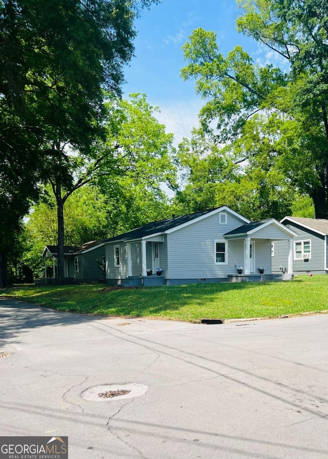 view of front of house featuring a front lawn and view of wooded area
