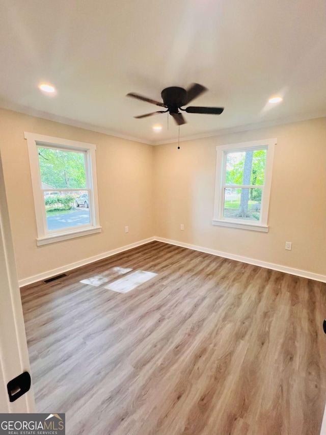 spare room with wood finished floors, baseboards, ceiling fan, recessed lighting, and crown molding