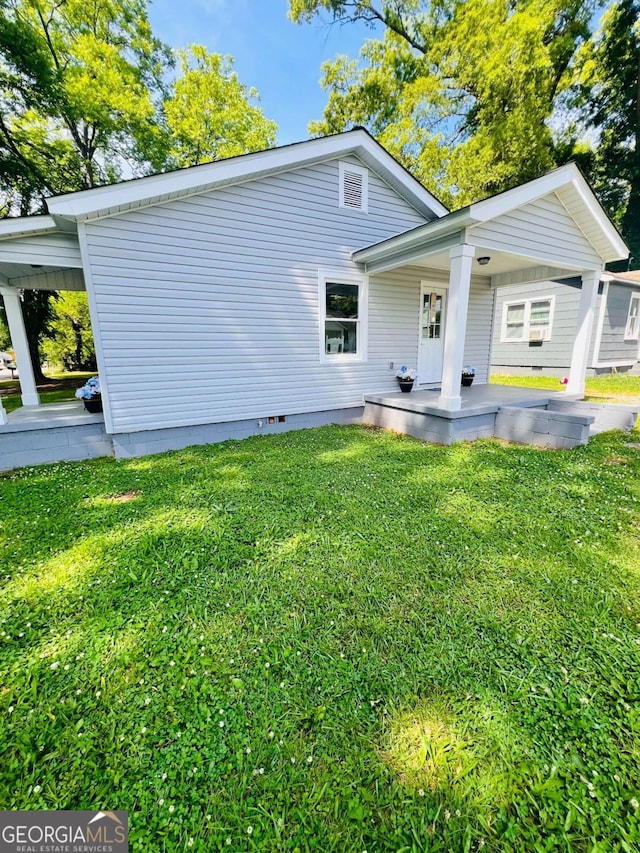 rear view of property with a porch, a yard, and crawl space