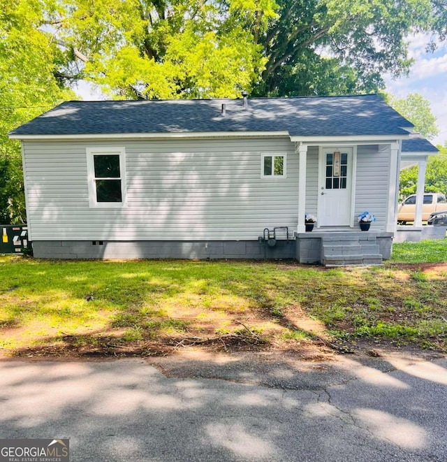 back of house featuring roof with shingles and crawl space