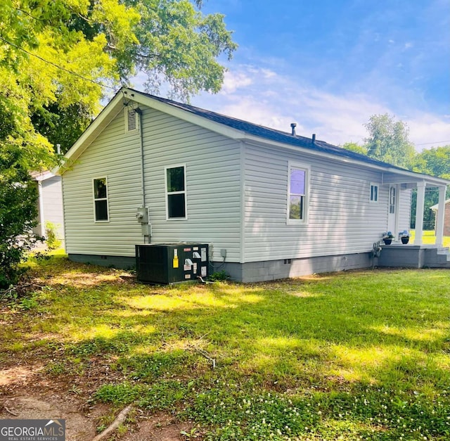 rear view of house featuring crawl space, central AC, and a yard