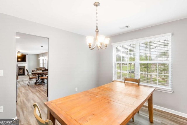 1194 Grandview Cir, Powder Springs, GA 30127 - dining room with light wood-type flooring, a chandelier, baseboards, and a fireplace