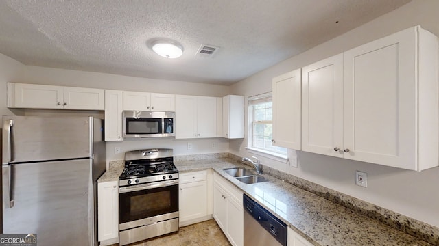 4162 Ward Lake Trl, Ellenwood, GA 30294 - kitchen featuring stainless steel appliances, a sink, white cabinets, a textured ceiling, and light stone countertops