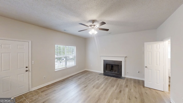 4162 Ward Lake Trl, Ellenwood, GA 30294 - unfurnished living room featuring light wood-type flooring, a ceiling fan, a fireplace with flush hearth, a textured ceiling, and baseboards