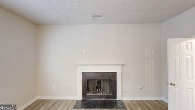 4162 Ward Lake Trl, Ellenwood, GA 30294 - detailed view of wood finished floors, a fireplace, baseboards, and a textured ceiling