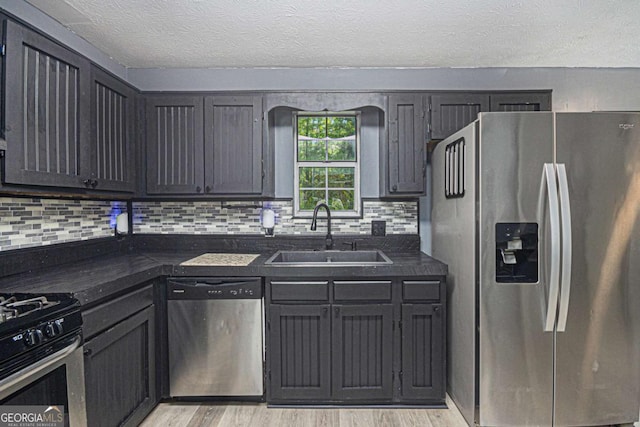 430 Pilgrim Ln, Powder Springs, GA 30127 - kitchen with stainless steel appliances, a sink, dark countertops, decorative backsplash, and light wood-type flooring