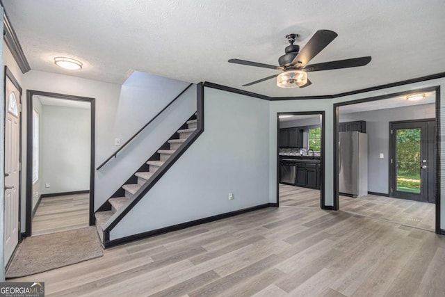 430 Pilgrim Ln, Powder Springs, GA 30127 - unfurnished living room featuring light wood finished floors, stairway, a textured ceiling, a ceiling fan, and baseboards