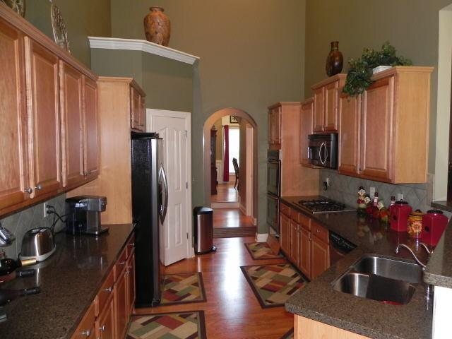 kitchen with freestanding refrigerator, arched walkways, stainless steel microwave, gas cooktop, and a sink