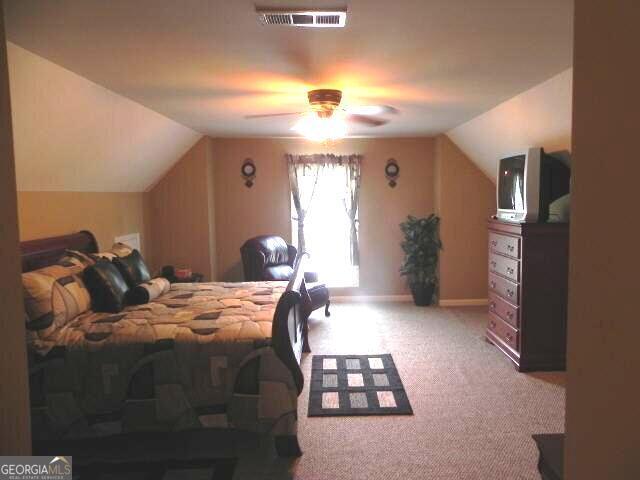 carpeted bedroom with lofted ceiling, baseboards, and a ceiling fan