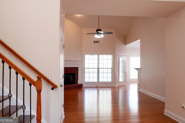 unfurnished living room featuring wood finished floors, a ceiling fan, a fireplace, baseboards, and stairs