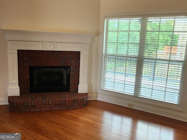 detailed view of baseboards, wood finished floors, and a brick fireplace