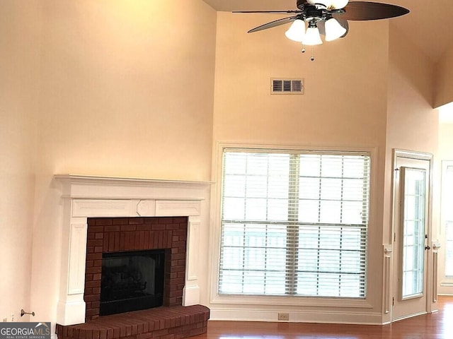 141 Windward Hls, Mcdonough, GA 30253 - living room featuring ceiling fan, wood finished floors, a brick fireplace, a high ceiling, and plenty of natural light