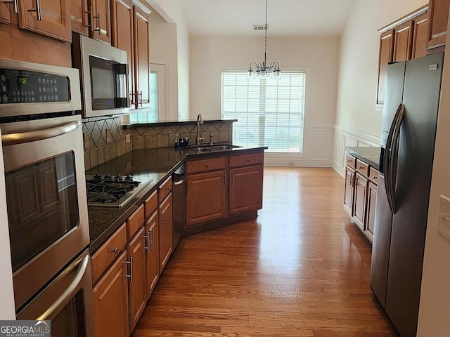 141 Windward Hls, Mcdonough, GA 30253 - kitchen featuring appliances with stainless steel finishes, a sink, a peninsula, wood finished floors, and a chandelier