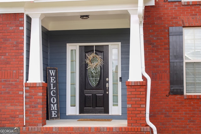 view of exterior entry with brick siding and covered porch