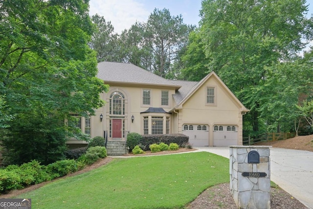 10660 Dunoon Dr, Alpharetta, GA 30022 - view of front facade featuring stucco siding, concrete driveway, a front lawn, and a garage