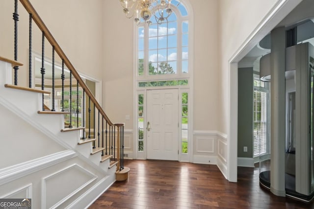 10660 Dunoon Dr, Alpharetta, GA 30022 - entryway featuring a chandelier, a high ceiling, stairs, dark wood-type flooring, and a wainscoted wall
