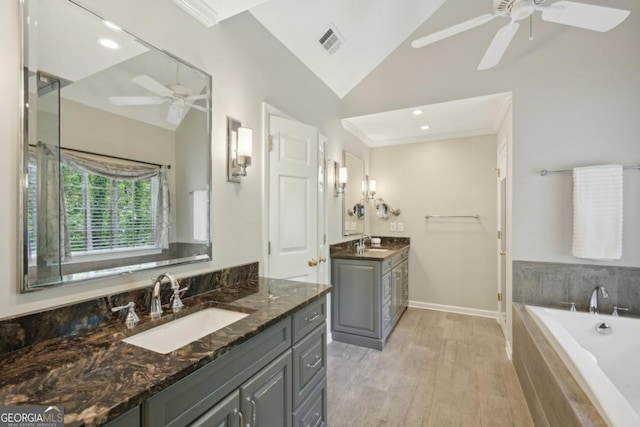 10660 Dunoon Dr, Alpharetta, GA 30022 - bathroom with ceiling fan, vaulted ceiling, a bath, two vanities, and wood finished floors