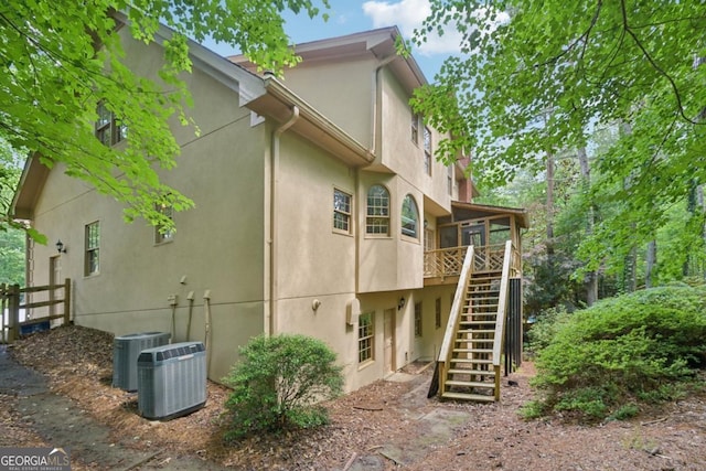 10660 Dunoon Dr, Alpharetta, GA 30022 - back of house with stairway, stucco siding, central AC, and a sunroom